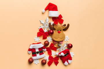 Christmas tree made from colored suit santa decoration on colored background, view from above. New Year minimal concept with copy space