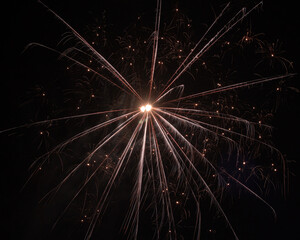 Obraz premium Flare from fireworks with rays of orange light from the centre and a lot of sparks on a black background
