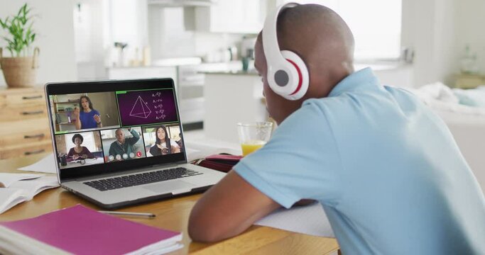 Video of african american boy with headphones having online lessons on laptop