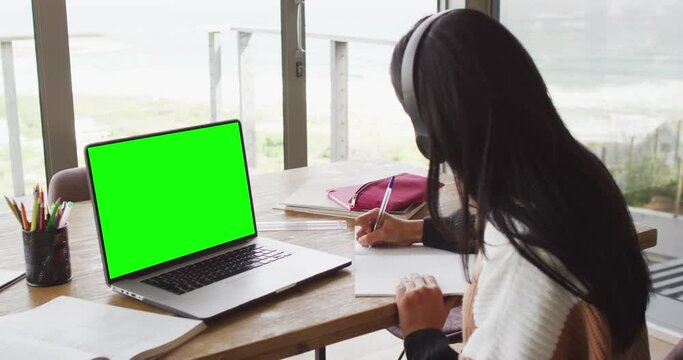 Animation of middle eastern girl in headphones having online lessons on laptop with copy space