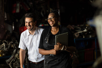 African American female worker and man customer choose and inspecting car part products while working in a old car part warehouse store.