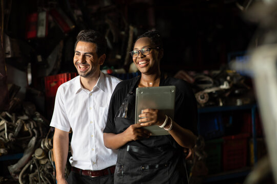 African American female worker and man customer choose and inspecting car part products while working in a old car part warehouse store.