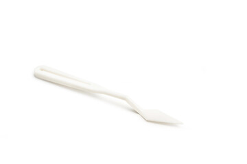 Espátula de plástico blanca sobre un fondo blanco liso y aislado. Vista de frente y de cerca. Copy space