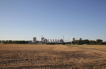 Fototapeta na wymiar Straight view from a field on a big nuclear power plant with blue sky in background