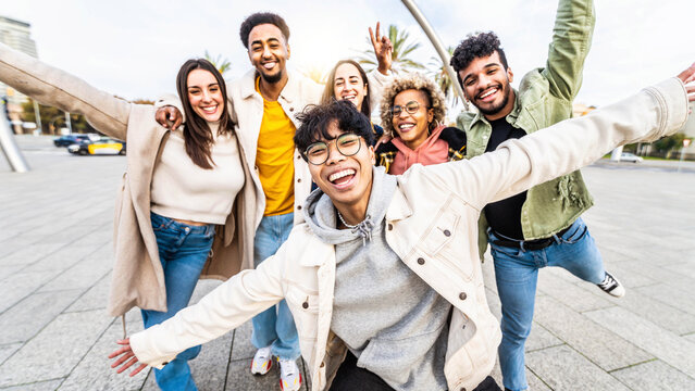 Happy multiracial friends having fun walking on city street - Group of young people hanging outside together - Friendship concept with guys and girls enjoying day out