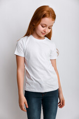 Redhead little girl model posing in white t-shirt on grey background