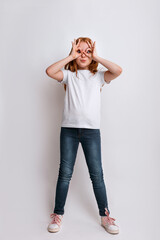 Cheerful redhead girl holding her hands near her eyes in the form of a mask wearing in white t-shirt