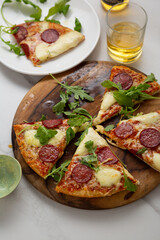 Sliced italian salami pizza on wooden board top view on stone surface