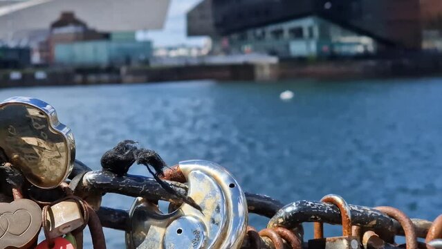 Modern and classic architecture is revealed behind love padlocks at the Liverpool Docks, Port of Liverpool on a beautiful spring day

