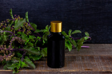 Holy Basil or Tulsi Essential Oil in bottle with Branch of Holy Basil on wooden background.
