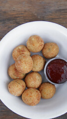 Fritters. Top view of potato and mozzarella cheese croquettes with sweet chili dipping sauce, in a white bowl on the wooden table.