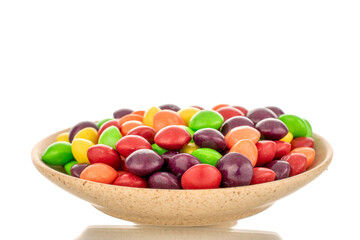 A lot of sweet colored candies on a ceramic saucer, close-up, isolated on a white background.