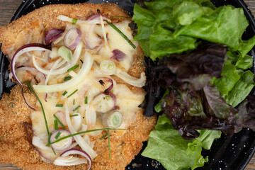 Top view of a milanesa, breaded steak, and a fresh lettuce salad.