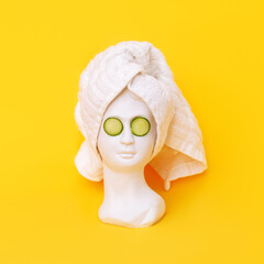 Antique female statue's head with a white towel after a shower and cucumber slices on her eyes...