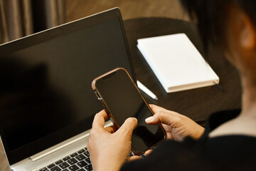 Mujer latina usando su telefono movil mientras trabaja desde casa. Concepto de tecnologia.