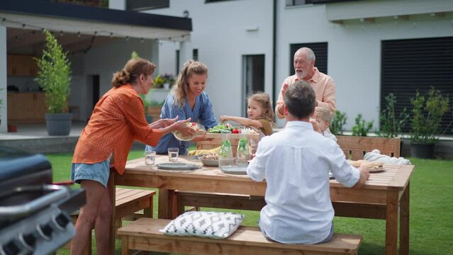 Family having garden party celebration, children are eating snacks, laughing and having fun.