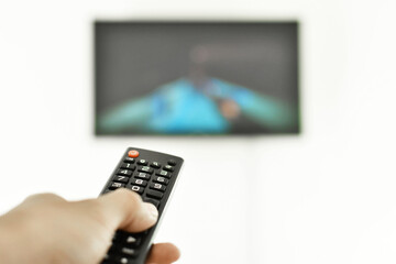 Persona utilizando el control remoto mientras mira television.