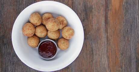 Cheese balls. Top view of potato and mozzarella cheese croquettes with sweet chili dipping sauce, in a white bowl on the wooden table.