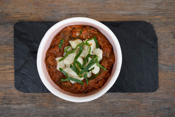 Top view of traditional goulash stew, with veil and gnocchi in a bowl on the wooden table.