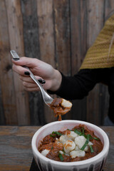 Eating at the restaurant. Closeup view of a woman holding a fork with having goulash stew made with veal, sauce and gnocchi.	
