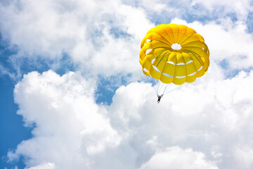 Paragliding using a parachute on background of blue cloudy sky.