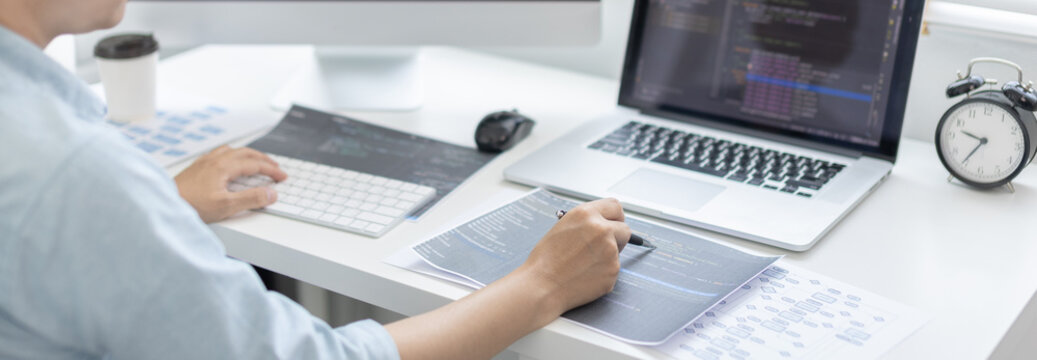 Professional development programmers are laying out a structure or draft on paper in preparation for coding on a computer, Write information or code for the website,  HTML, javascript, Software.