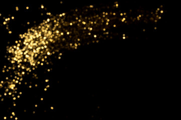 Fototapeta na wymiar Golden blurred bokeh lights on black background. Glitter sparkle stars for celebrate. Overlay for your design