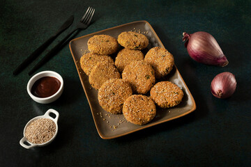Nuggets (croquettes) with gluten free bread crumb and sesame seeds on a dark background. 