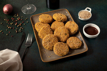 Nuggets (croquettes) with gluten free bread crumb and sesame seeds on a dark background. 