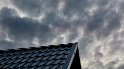 Fototapeta na wymiar Construction of the roof of the house. Metal tiles against evening sky