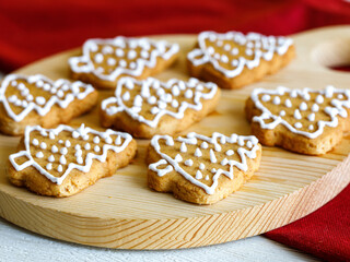 Homemade gingerbread cookie in shape of Christmas Tree decorated with icing on wooden cutting board. Traditional Christmas food. Christmas and New Year holiday concept.