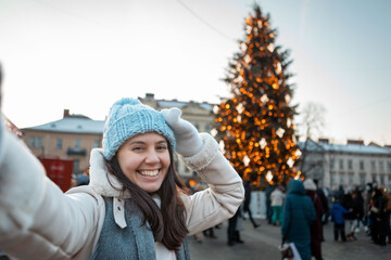 Fototapeta na wymiar beautiful smiling women taking selfie picture at city square christmas tree on background