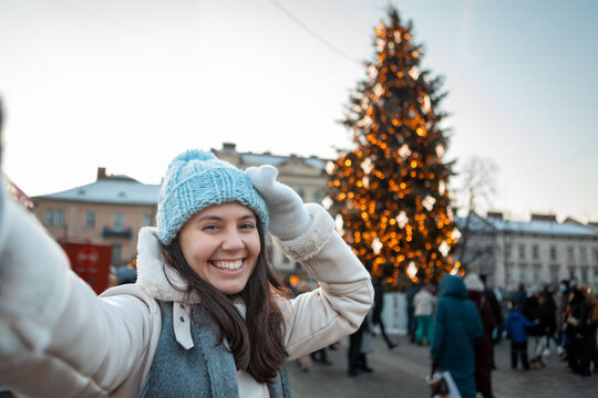 beautiful smiling women taking selfie picture at city square christmas tree on background