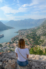Naklejka premium Woman tourist enjoys the view of Kotor bay. Back view.
