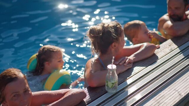 Multi generation family having fun and enjoying swimming in backyard pool during summer holiday.