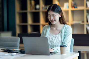 Obraz na płótnie Canvas Young Business Asian woman sitting at a desk with a laptop and working in the home office or her workplace, accountant tax contract report analysis document data Audit concept.