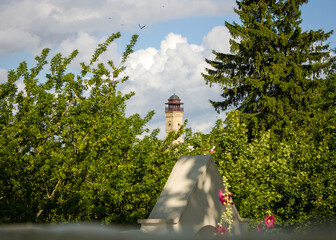  Neighborhood of Grodno, Belarus. Summer landscape with the top of a fire tower surrounded by green leaves against a blue cloudy sky.