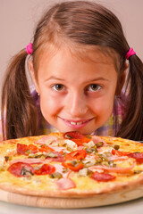 Kids' pizza. Close up portrait of happy young beautiful child girl holding pizza.