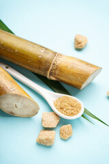 Sugar cane and brown sugar pieces on blue background. Close-up. Vertically.