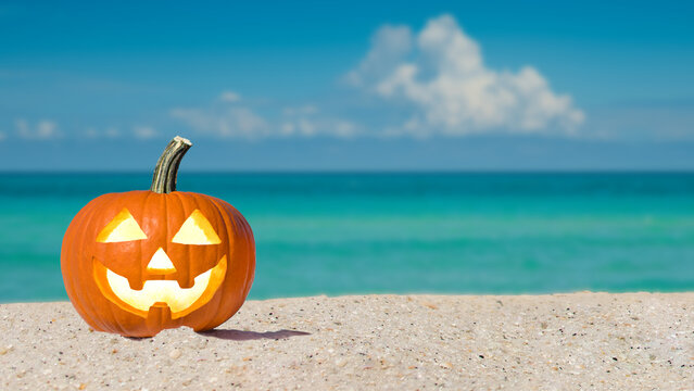 Happy Halloween. Pumpkin Jack-o'-lantern on the beach. Jack o lantern for Halloween party. Autumn season. Blue ocean on background. Autumn season. Florida beach. Copy space.