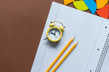 Yellow pencils and clock on open notebook. Back to school, education concept background	