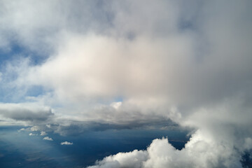 Fototapeta na wymiar Aerial view from airplane window at high altitude of earth covered with puffy cumulus clouds forming before rainstorm