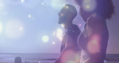 Animation of light spots over biracial couple at beach - Powered by Adobe
