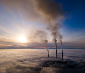 Naklejka na ściany i meble Aerial view of coal power plant high pipes with black smoke moving up polluting atmosphere at sunset