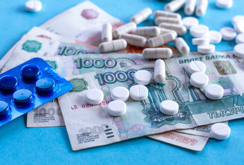 Pills (drugs) and Russian money on a blue background. The concept of health insurance, treatment payment, medical budget