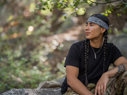 Horizontal portrait of an Indigenous man relaxing and smiling in the outdoors 