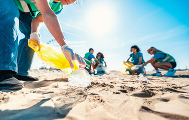 Group of eco volunteers picking up plastic trash on the beach - Activist people collecting garbage...