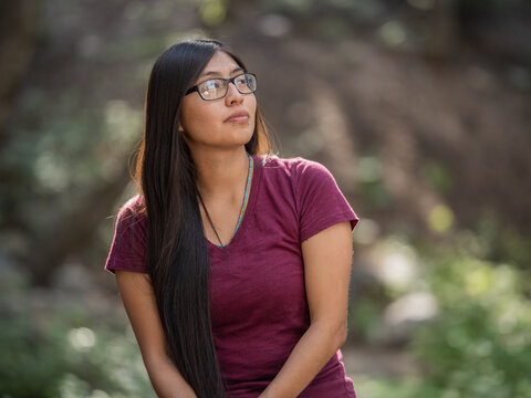 Horizontal portrait of a young Indigenous woman sitting in the outdoors 