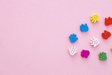 Colored wooden figures in the form hand with smiles on a pink background