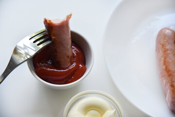 Fried meat sausage with sauces on a white background. Delicious meat breakfast with mayonnaise and ketchup.